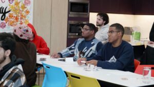A group of male youth sitting at tables looking away from camera.